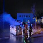 Löschmaßnahmen an dem brennenden Papiercontainer