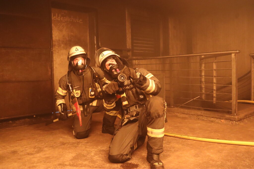 Das Bild zeigt Einsatzkräfte bei einer Übung im Brandhaus.